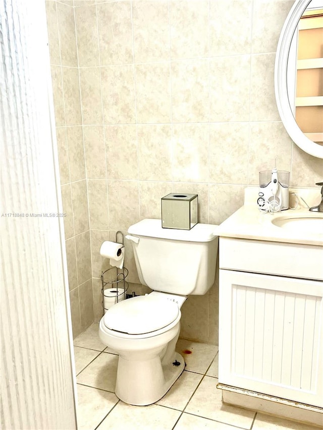 bathroom featuring tile patterned floors, vanity, toilet, and tile walls