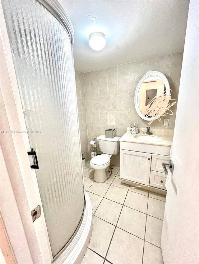 bathroom featuring tile patterned floors, vanity, an enclosed shower, and tile walls