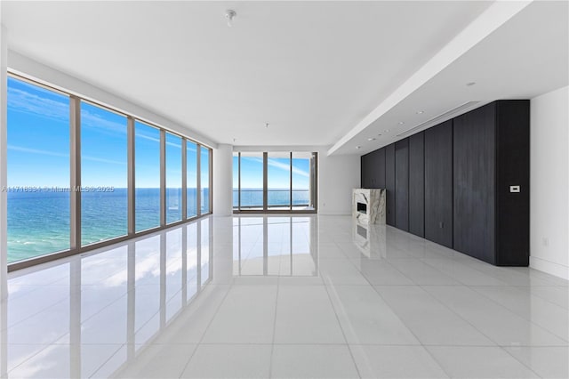 spare room featuring light tile patterned flooring, a water view, and floor to ceiling windows