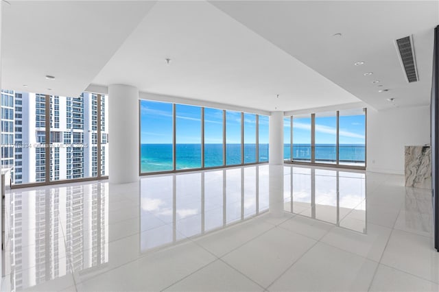 tiled spare room with a water view, plenty of natural light, and floor to ceiling windows