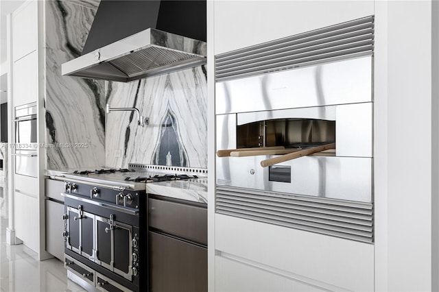 kitchen featuring white cabinets, stainless steel gas stovetop, oven, and range hood