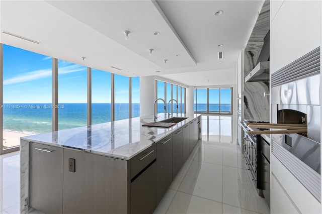 kitchen with white cabinets, a water view, a large island, and a beach view