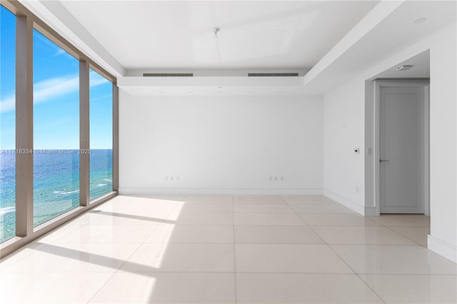 tiled spare room featuring floor to ceiling windows and a water view