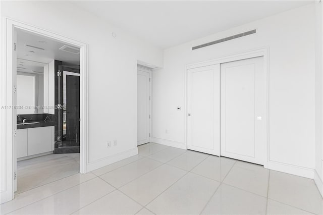 unfurnished bedroom featuring a closet, light tile patterned flooring, and sink