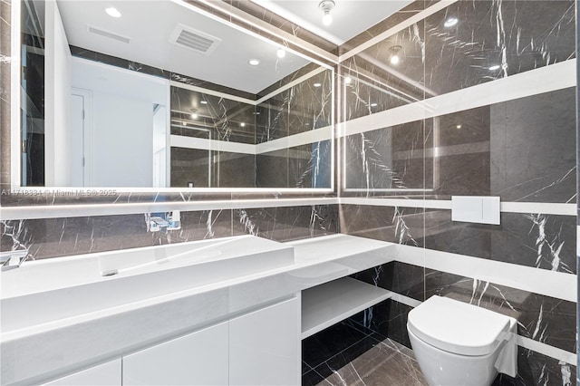 bathroom with vanity, toilet, and tile walls