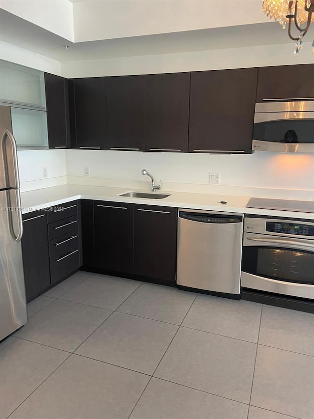 kitchen with light tile patterned flooring, stainless steel appliances, a notable chandelier, and sink