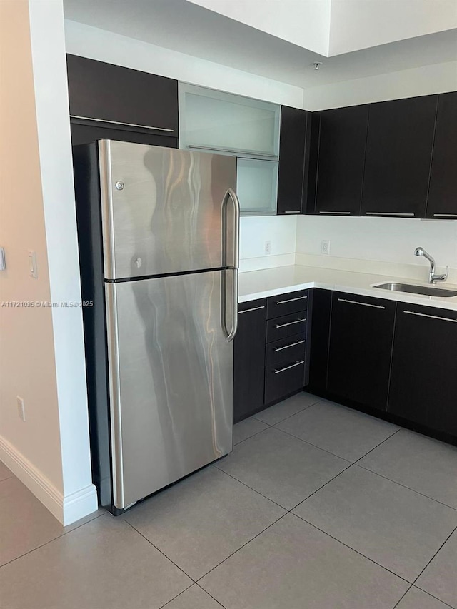 kitchen featuring stainless steel refrigerator, sink, and light tile patterned flooring