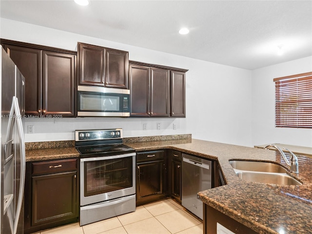 kitchen with dark brown cabinetry, sink, stainless steel appliances, kitchen peninsula, and light tile patterned floors