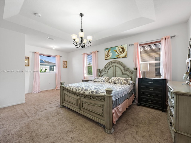 carpeted bedroom featuring a tray ceiling and a notable chandelier