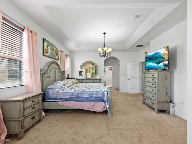 bedroom featuring a raised ceiling, a chandelier, and light colored carpet