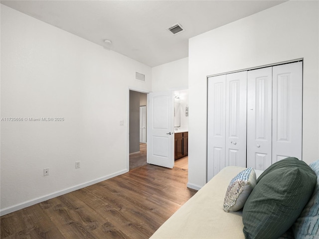 bedroom with hardwood / wood-style flooring, ensuite bath, and a closet