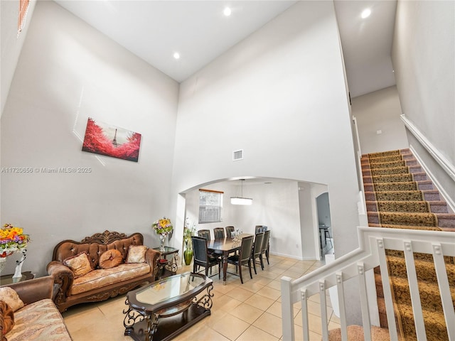 living room with light tile patterned flooring and a towering ceiling