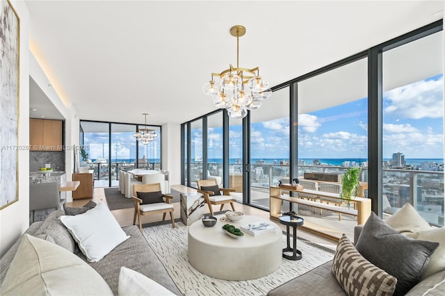 living room featuring an inviting chandelier, a wall of windows, and a water view