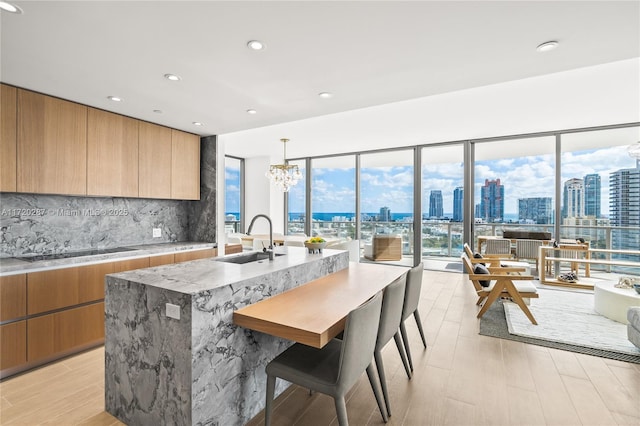 kitchen featuring decorative light fixtures, black electric cooktop, a kitchen island with sink, a kitchen breakfast bar, and sink