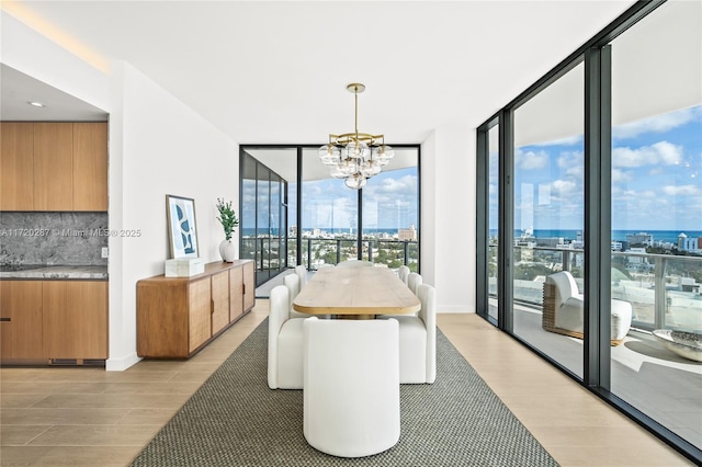 dining area with floor to ceiling windows, light wood-type flooring, and a notable chandelier