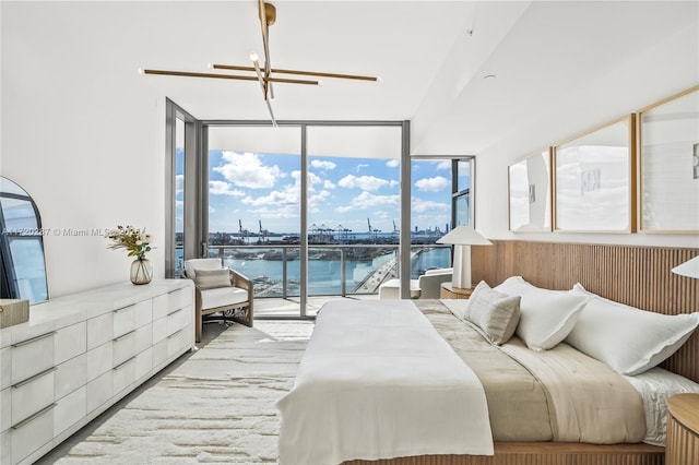 bedroom with ceiling fan with notable chandelier, access to exterior, expansive windows, and a water view