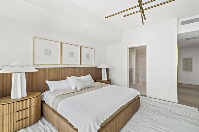 bedroom featuring ensuite bath and light hardwood / wood-style floors