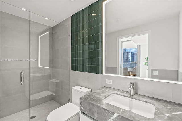 bathroom featuring toilet, an enclosed shower, vanity, and tile walls