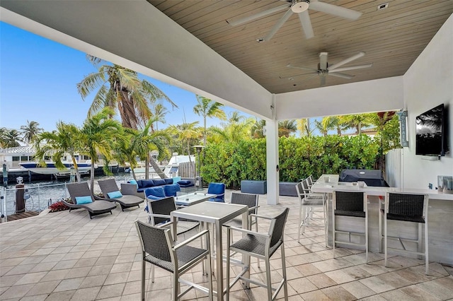 view of patio with a water view, outdoor lounge area, ceiling fan, and a bar