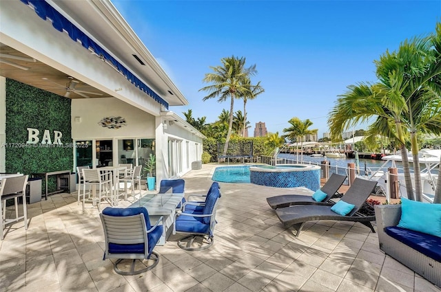 view of swimming pool featuring ceiling fan, a water view, an in ground hot tub, a patio area, and exterior bar