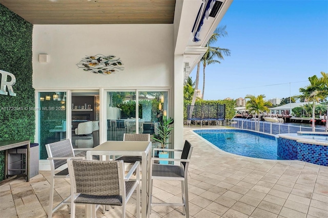 view of pool featuring an in ground hot tub, a trampoline, and a patio