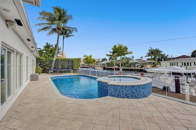 view of swimming pool featuring a trampoline, a patio area, an in ground hot tub, and a water view