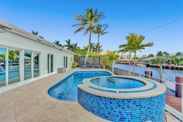 view of swimming pool with an in ground hot tub, a water view, and a trampoline