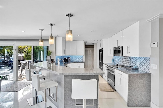 kitchen with white cabinetry, hanging light fixtures, a breakfast bar, and high quality appliances