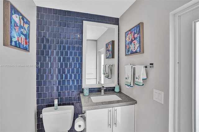 bathroom with vanity, toilet, and tile walls