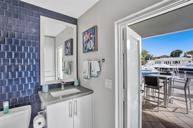 bathroom featuring vanity, tile walls, and toilet