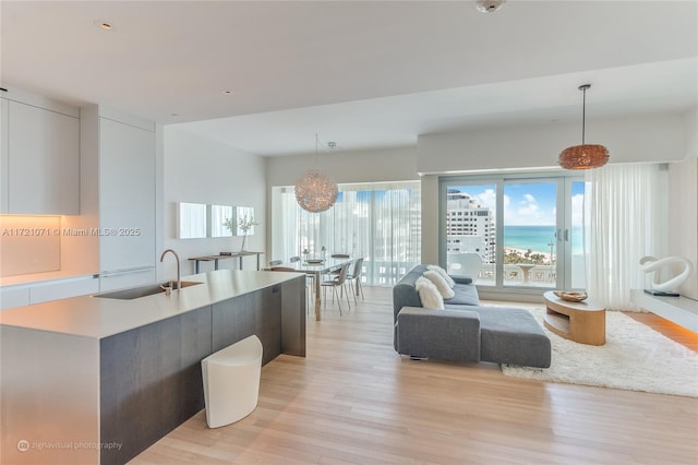 kitchen with a center island with sink, decorative light fixtures, light hardwood / wood-style floors, and sink