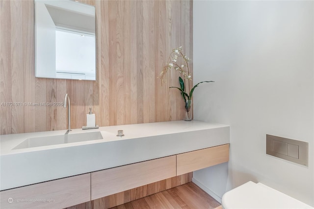 bathroom featuring wooden walls, vanity, and toilet