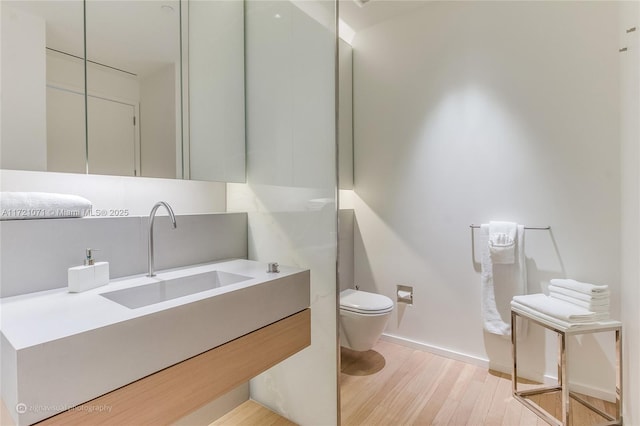 bathroom with hardwood / wood-style floors, vanity, and toilet