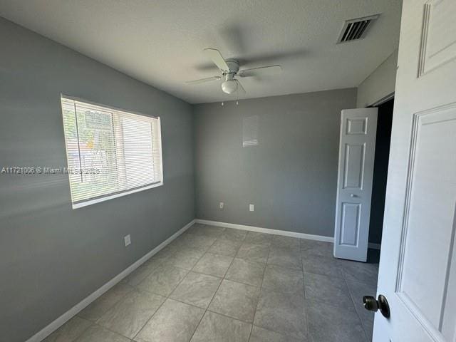 tiled empty room featuring ceiling fan