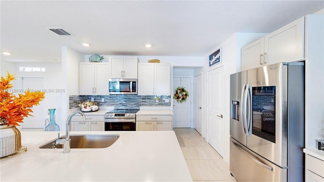 kitchen with white cabinetry, appliances with stainless steel finishes, sink, and backsplash