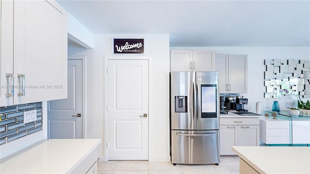 kitchen with stainless steel refrigerator with ice dispenser, light tile patterned floors, and white cabinets