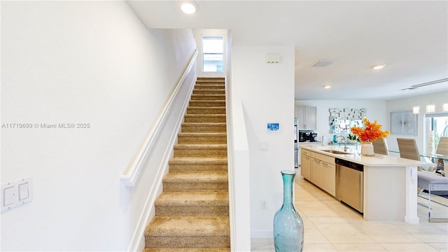 stairway featuring tile patterned flooring, sink, and a wealth of natural light