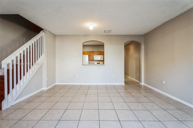 spare room with a textured ceiling and light tile patterned floors