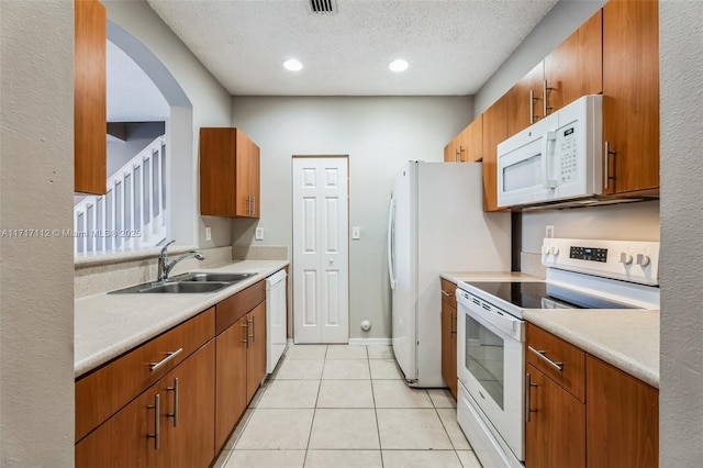 kitchen with sink, white appliances, a textured ceiling, and light tile patterned floors