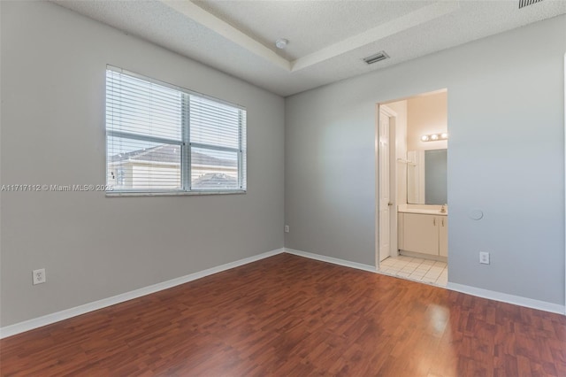 spare room featuring a textured ceiling and light hardwood / wood-style floors