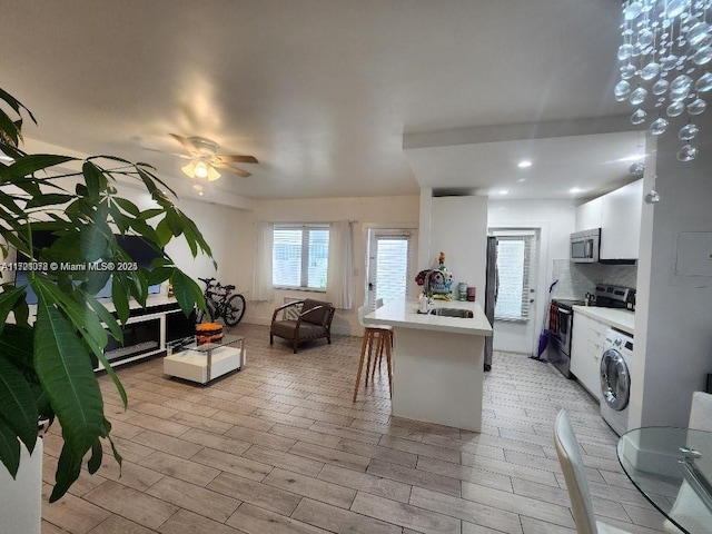 kitchen with white cabinets, sink, ceiling fan, appliances with stainless steel finishes, and washer / clothes dryer