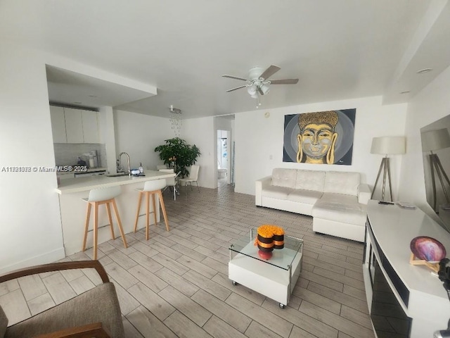 living room with light hardwood / wood-style floors, ceiling fan, and sink