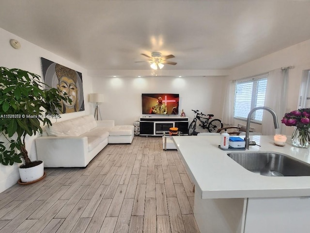 kitchen with ceiling fan, sink, and light hardwood / wood-style floors