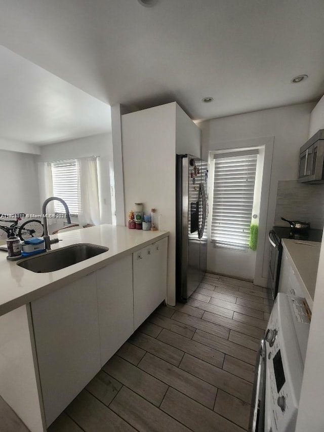 kitchen with kitchen peninsula, sink, white cabinets, and appliances with stainless steel finishes