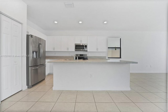 kitchen featuring white cabinets, light tile patterned flooring, an island with sink, and stainless steel appliances