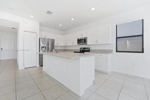 kitchen with white cabinetry, an island with sink, light tile patterned floors, and appliances with stainless steel finishes