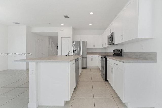 kitchen with a center island with sink, white cabinets, sink, light tile patterned floors, and stainless steel appliances