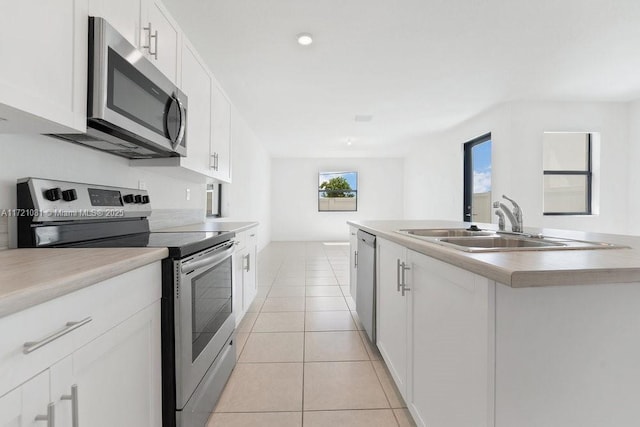 kitchen with white cabinetry, sink, stainless steel appliances, a center island with sink, and light tile patterned floors