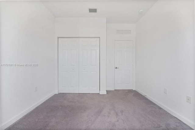 unfurnished bedroom featuring light carpet and a closet