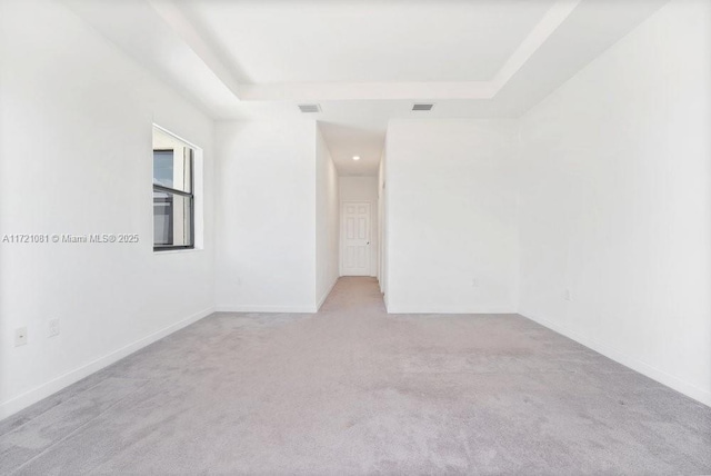 carpeted empty room featuring a raised ceiling